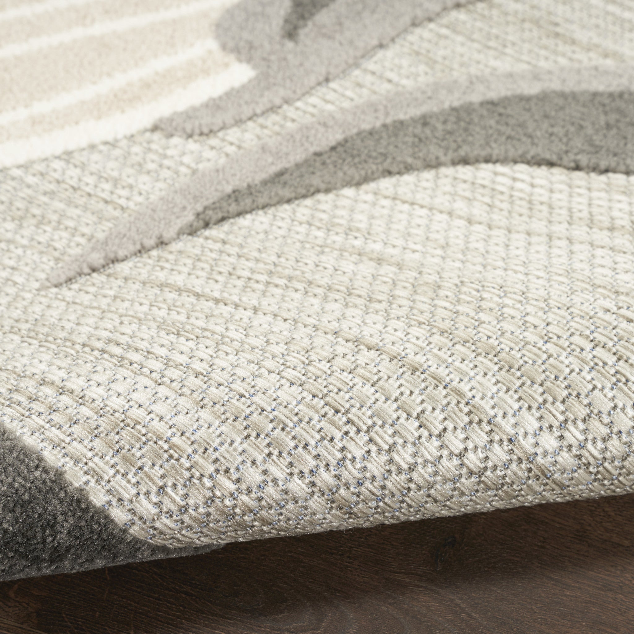 Beige area rug surface texture close-up with subtle woven grid pattern