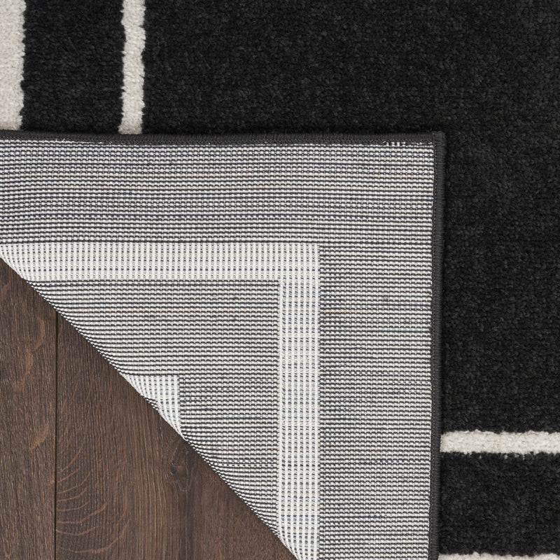 Black and ivory rug with textured weave, corner showing underside edge