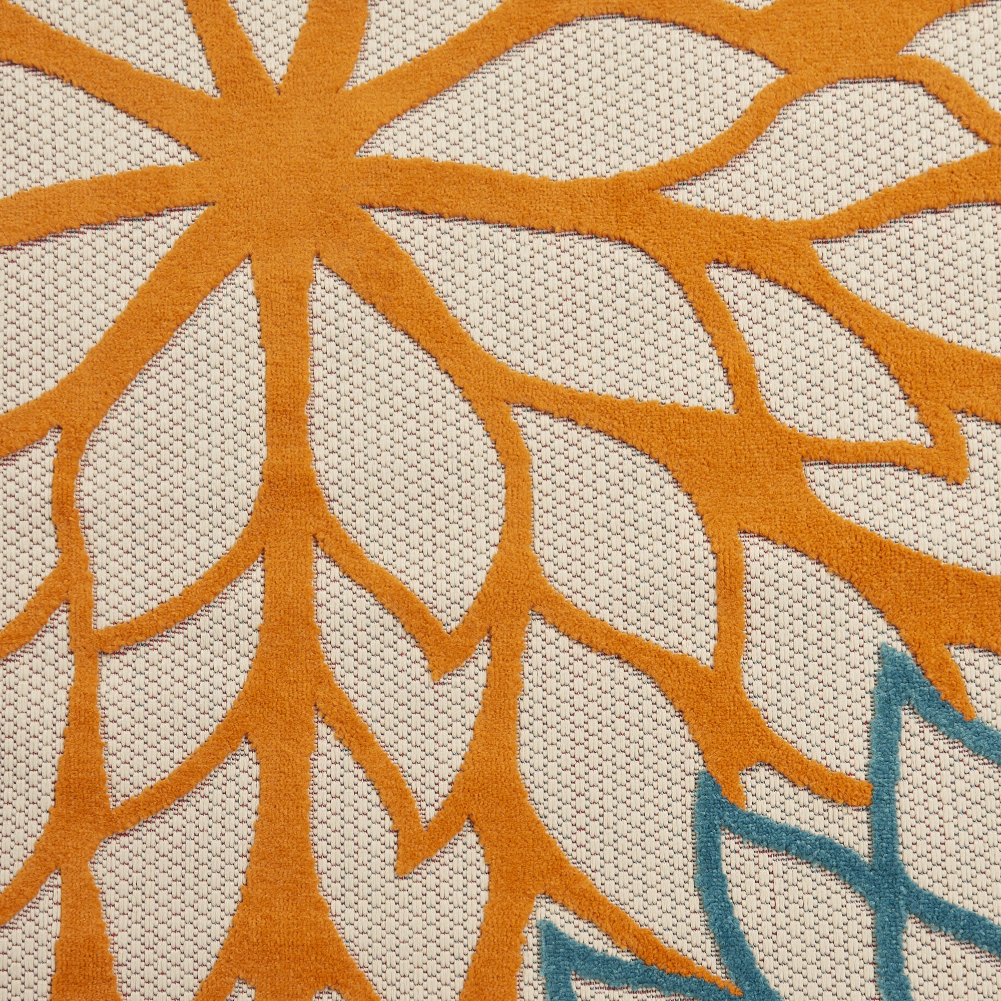 Ivory floral area rug close-up with orange sunburst petals and small blue accents