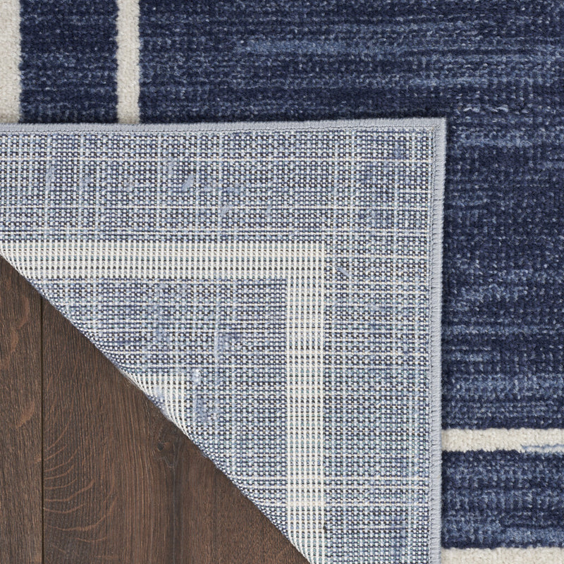 Navy area rug edge with ivory woven backing and border stripe detail