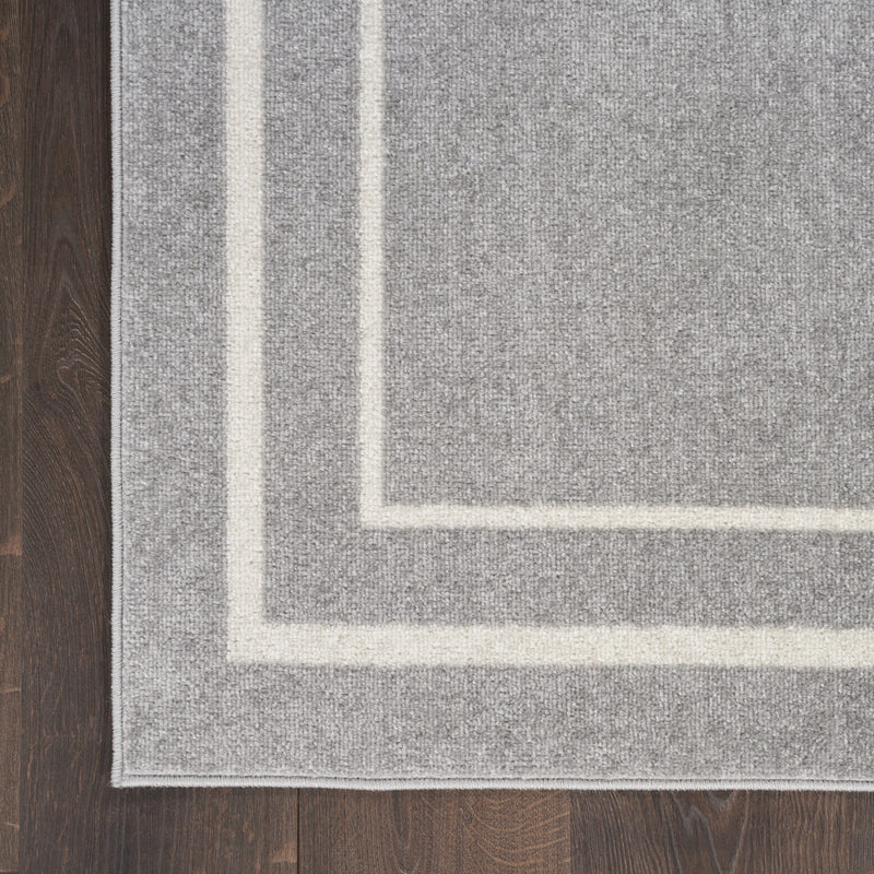Indoor/outdoor area rug corner with ivory border and grey field on textured pile.