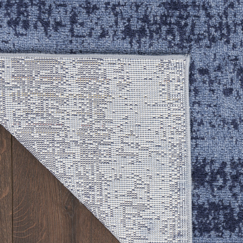 Abstract indoor/outdoor area rug, denim blue and white with textured flat weave, corner view