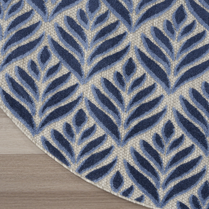 Corner view of blue and cream round rug with repeating leaf pattern