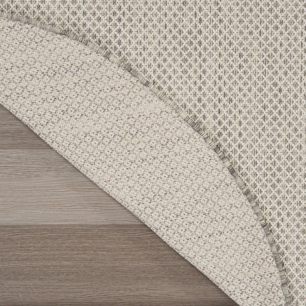 Close-up of round rug edge with woven speckled texture in ivory and gray