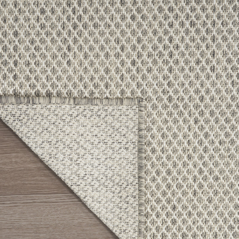 Reversible area rug edge with fringe; ivory underside shown next to diamond top
