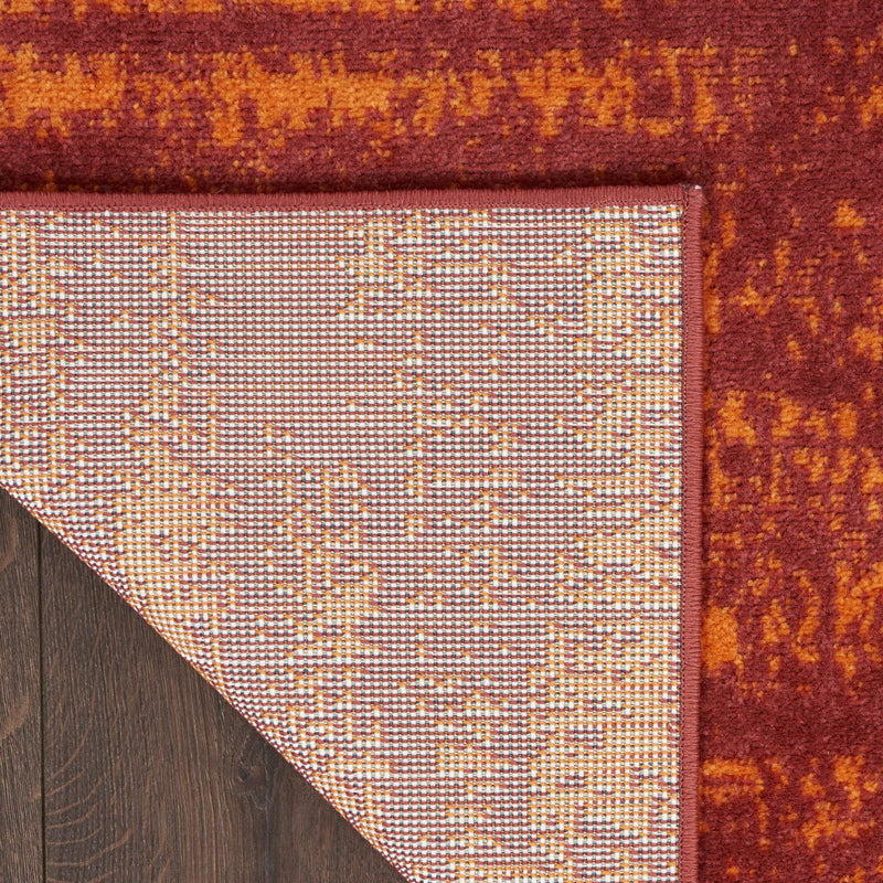 Red and orange abstract area rug corner with dark border and stitched edge