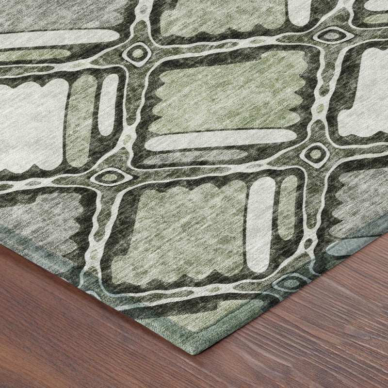 Corner of sage and green geometric area rug with textured pile and border lines