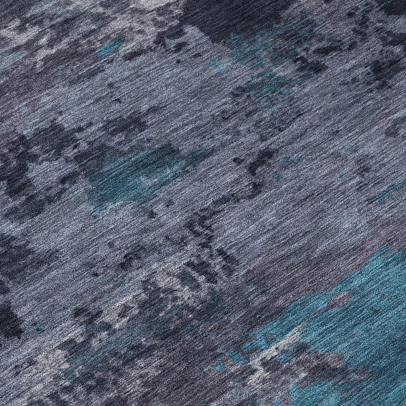 Close-up of teal-blue and graphite abstract area rug, speckled texture.