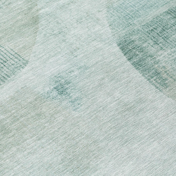 Round area rug with light teal and off-white abstract geometric pattern.