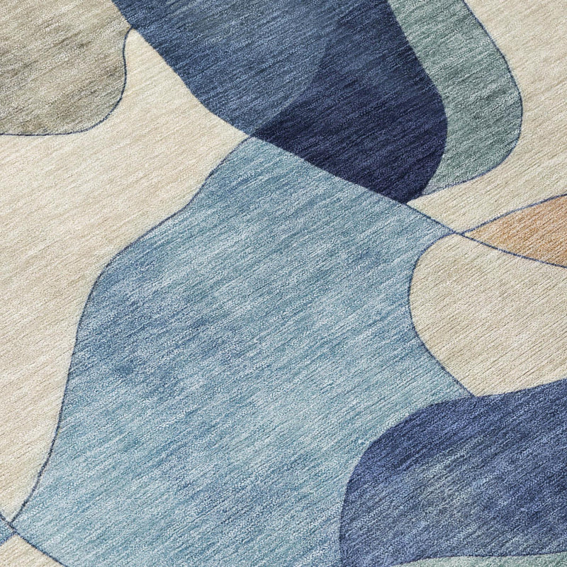 Closeup of round rug with layered curved geometric pattern in blue, tan, and muted green