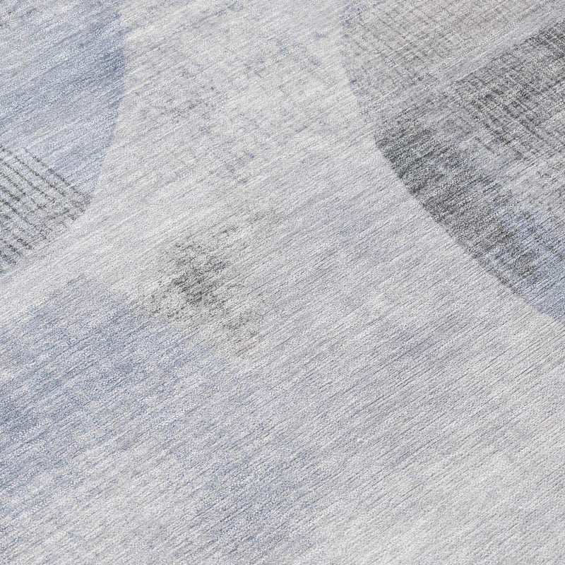 Close-up of geometric area rug texture in light gray with soft blue abstract shapes