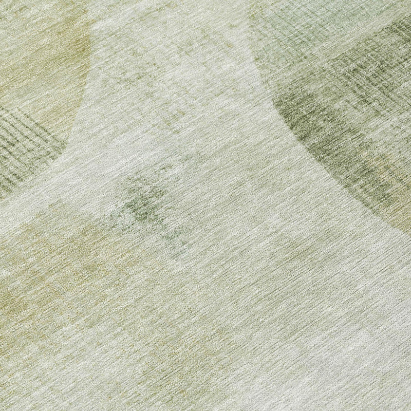 Round area rug close-up showing green and ivory abstract shapes and texture