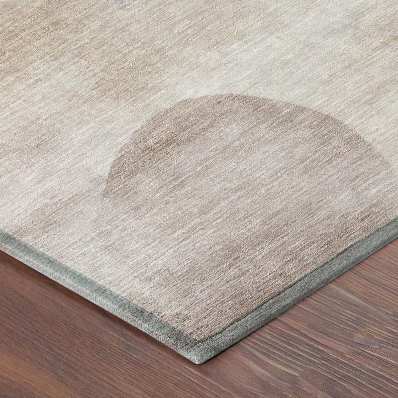 Corner view of beige round rug with abstract pattern and gray binding