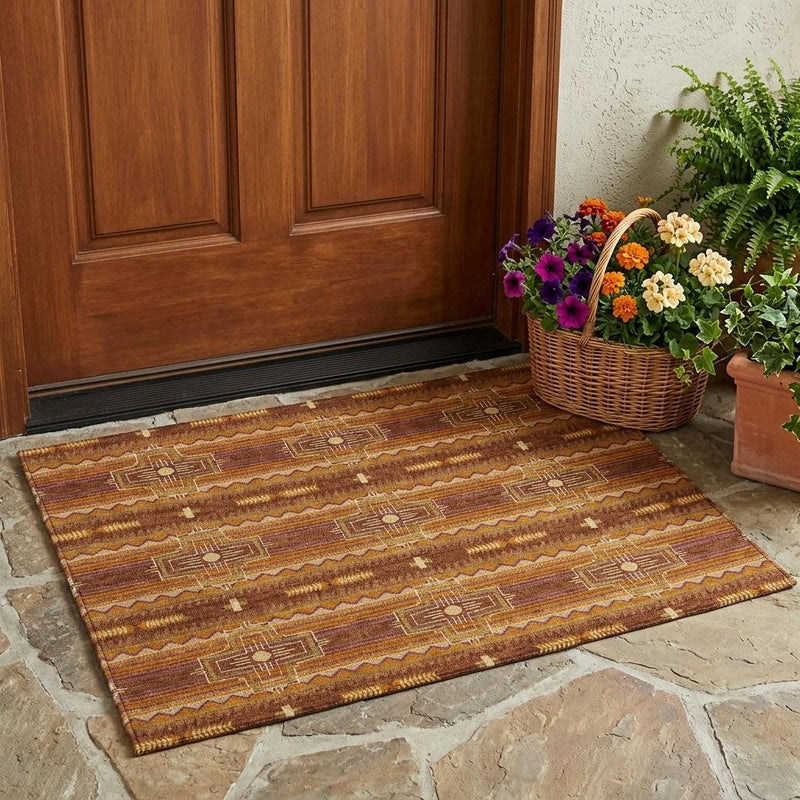 Tribal area rug in rust and brown with repeating geometric border, placed on stone.
