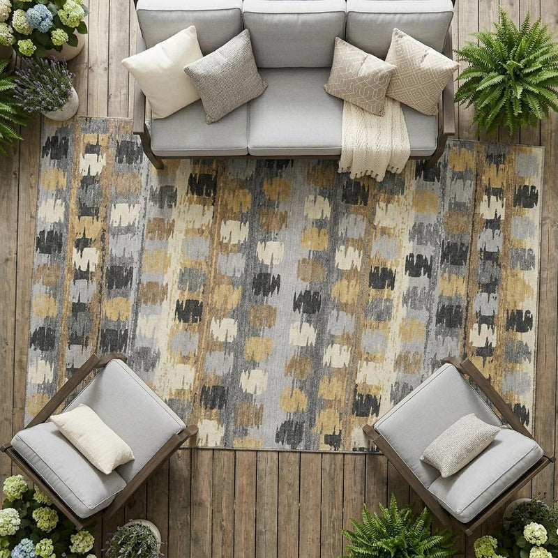 Abstract area rug with distressed gray, cream, black, and gold block design