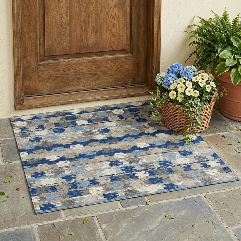 Abstract washable area rug with blue and charcoal shapes on a beige background.