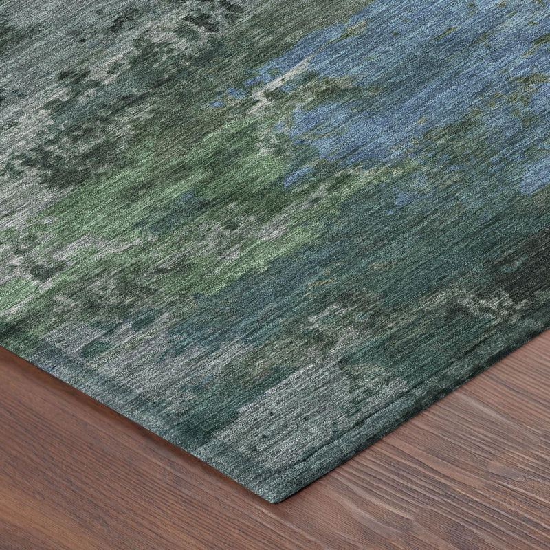 Close-up abstract area rug corner in green and graphite with scattered blue specks