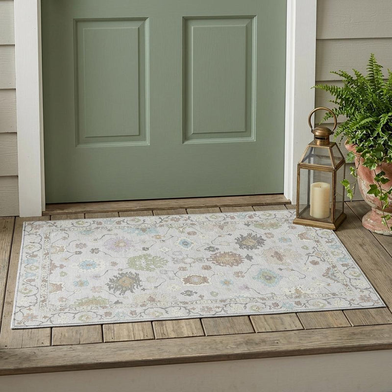 Gray oriental washable area rug on porch floor with multicolor pattern and border.