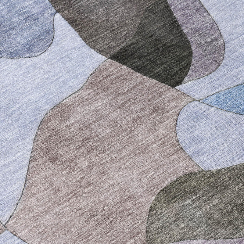 Round rug close-up: abstract wavy blocks in blue, gray, beige, and light tan.