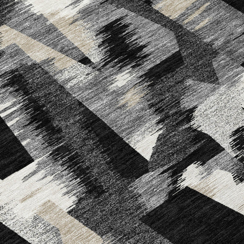 Abstract area rug surface with black, graphite, and beige brushstroke shapes.