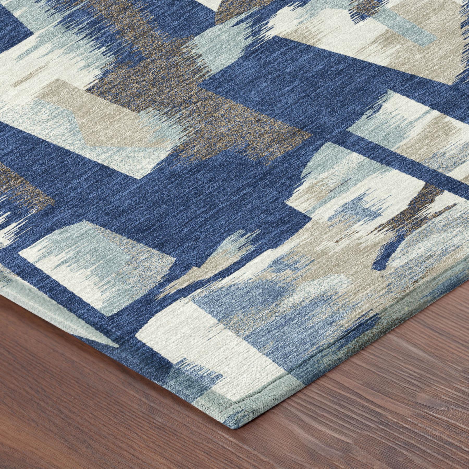 Blue and beige abstract area rug corner with stitched border edge on wood floor