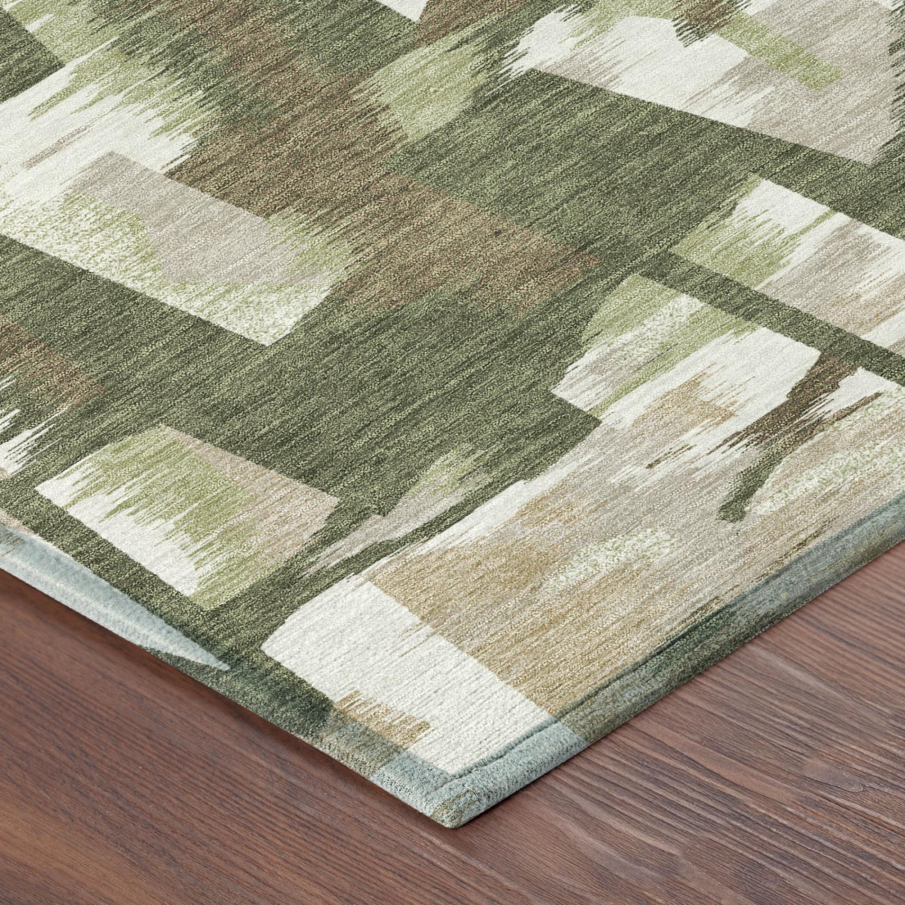 Corner view of olive green abstract rug with cream blocks and slightly fringed edge.