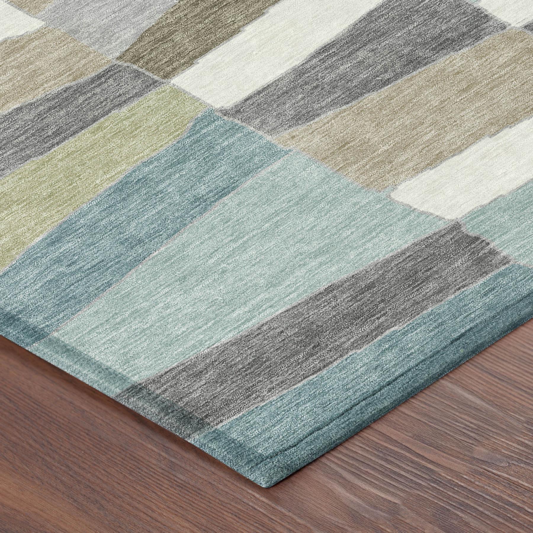 Corner of geometric patchwork area rug with teal, aqua, beige, gray, and cream blocks