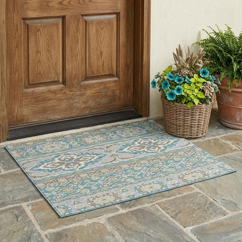 Teal and green tribal wash area rug on floor beside wooden door and planter