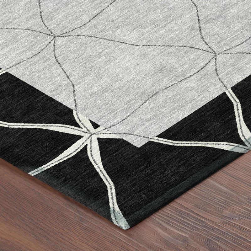 Corner of geometric area rug with black base, light gray diamonds, and white outline lines