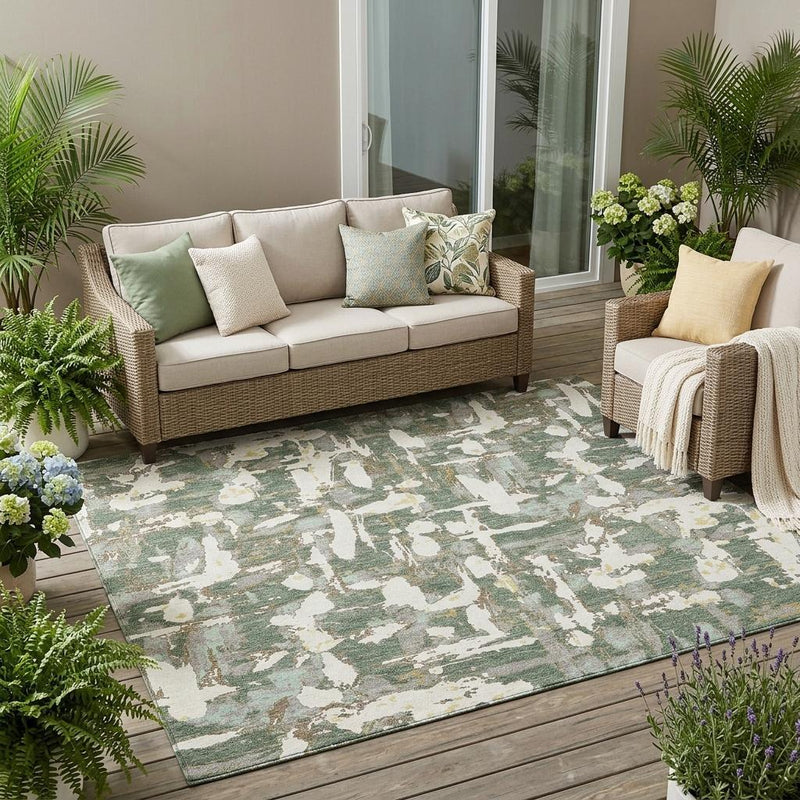 Indoor outdoor area rug with abstract green and beige distressed design on wooden deck