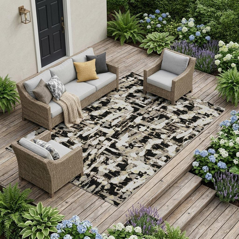 Outdoor abstract area rug on wood deck; black and copper pattern on cream.