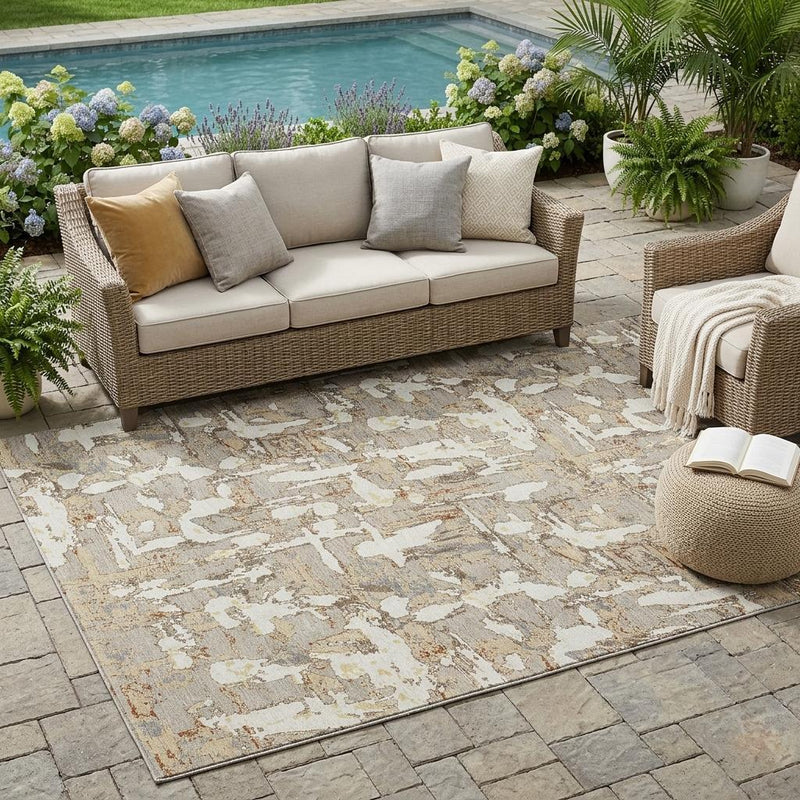 Beige and gray abstract area rug outdoors on stone patio with furniture around.