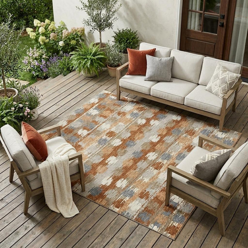 Indoor outdoor area rug with abstract orange, beige, and gray distressed pattern.