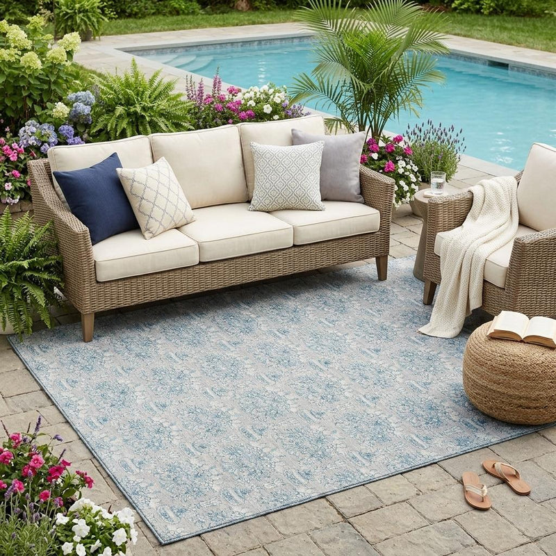Indoor outdoor area rug on patio with light gray and blue floral damask pattern