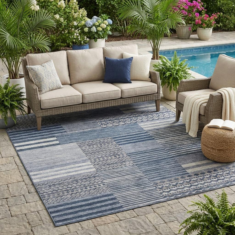 Blue and gray patchwork area rug laid outdoors with stripe and diamond motif panels