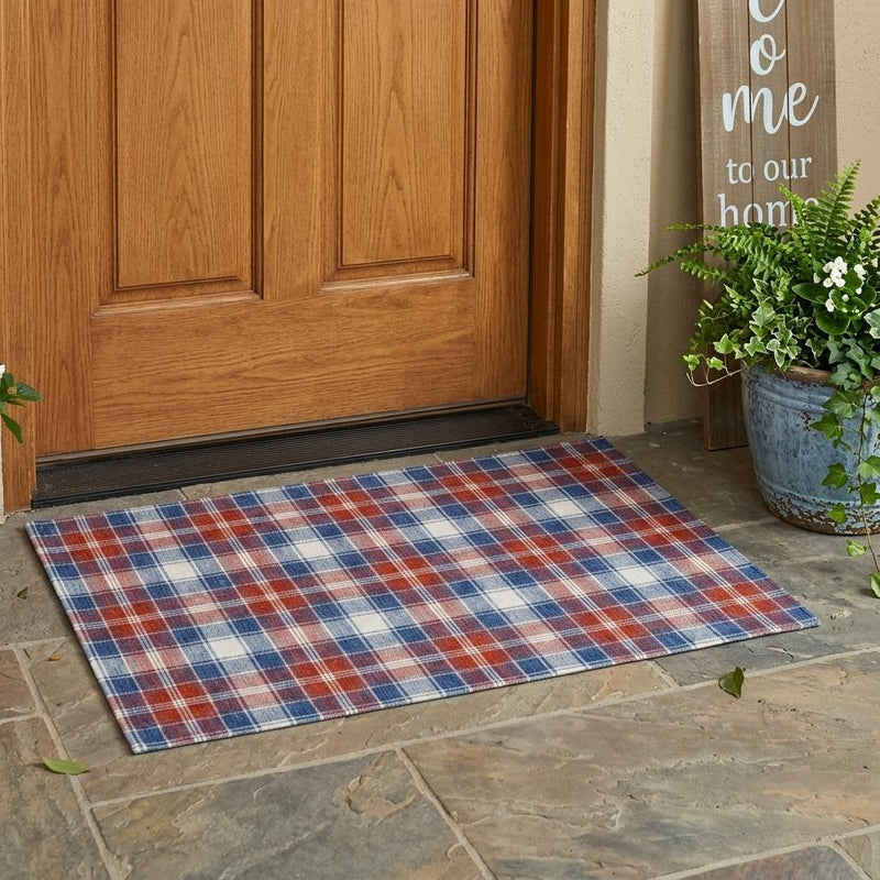Blue and ivory plaid area rug laid on stone patio near door, flat texture
