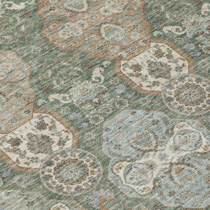 Diagonal close-up of green and silver floral geometric area rug with distressed pattern