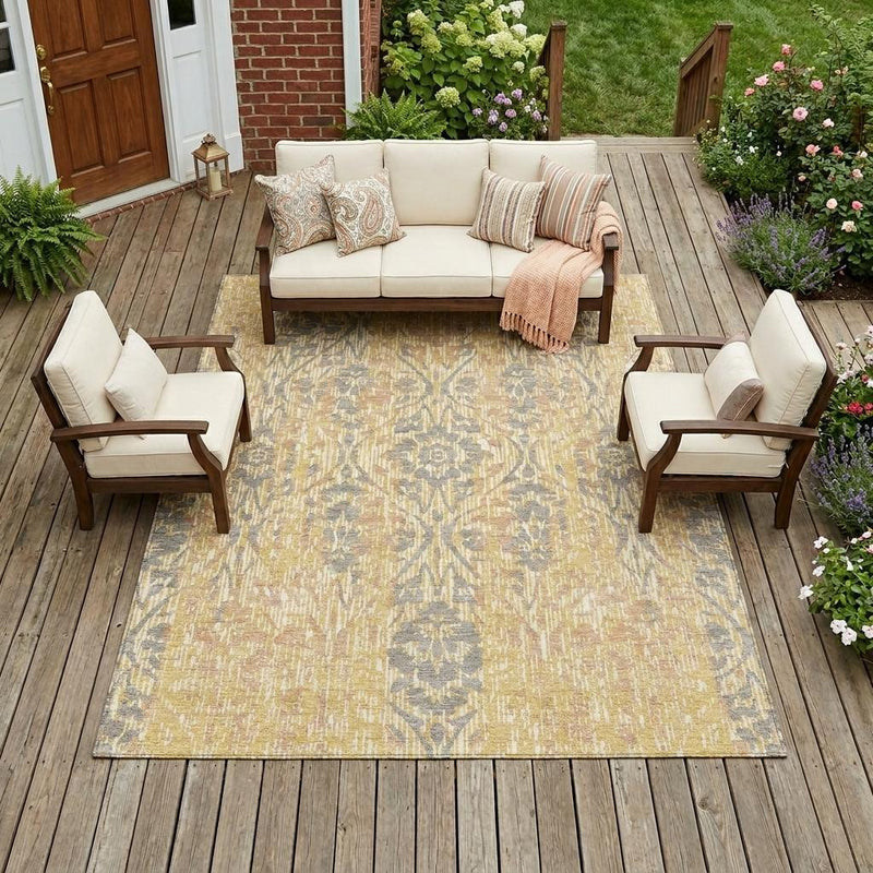 Gold and dark gray damask indoor outdoor area rug laid on a wooden deck