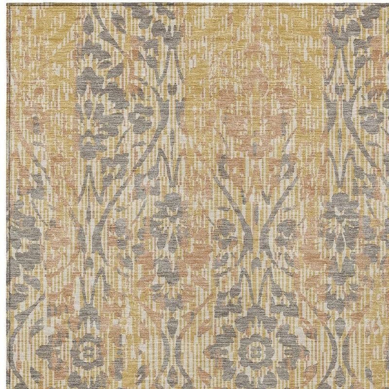 Close-up damask area rug pattern in gold, tan, and dark gray