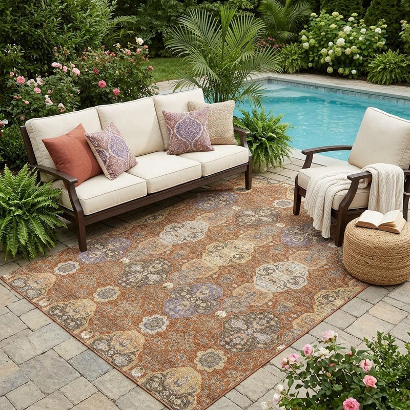 Orange and copper floral area rug laid outdoors on stone patio, shown with visible borders.