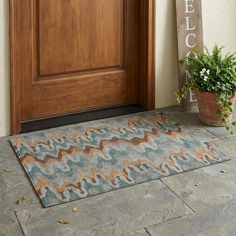 Indoor/outdoor area rug featuring abstract zigzag pattern in muted silver, copper, and teal