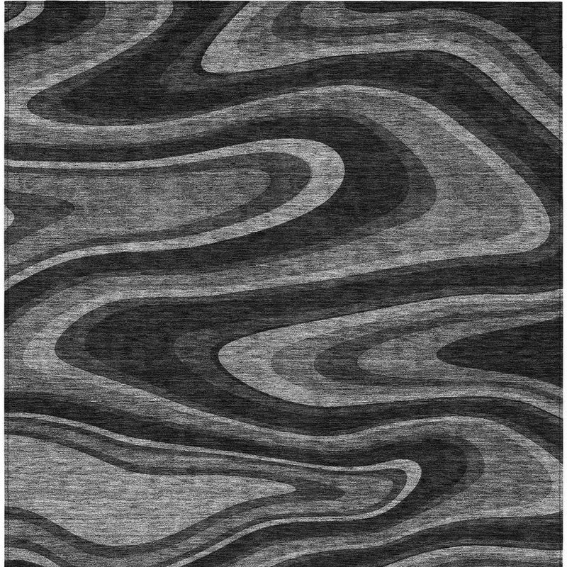 Close-up of black and gray abstract rug showing layered wavy lines and swirls.