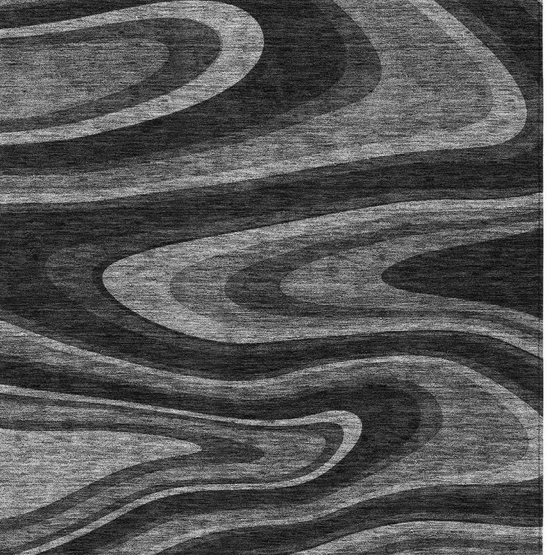 Black and charcoal abstract area rug featuring layered wavy curves in grayscale