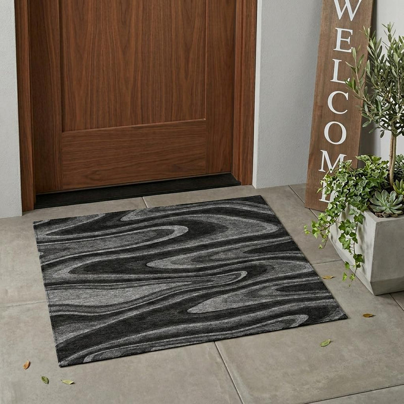 Rectangular black and charcoal abstract rug on indoor floor with wavy swirl motif