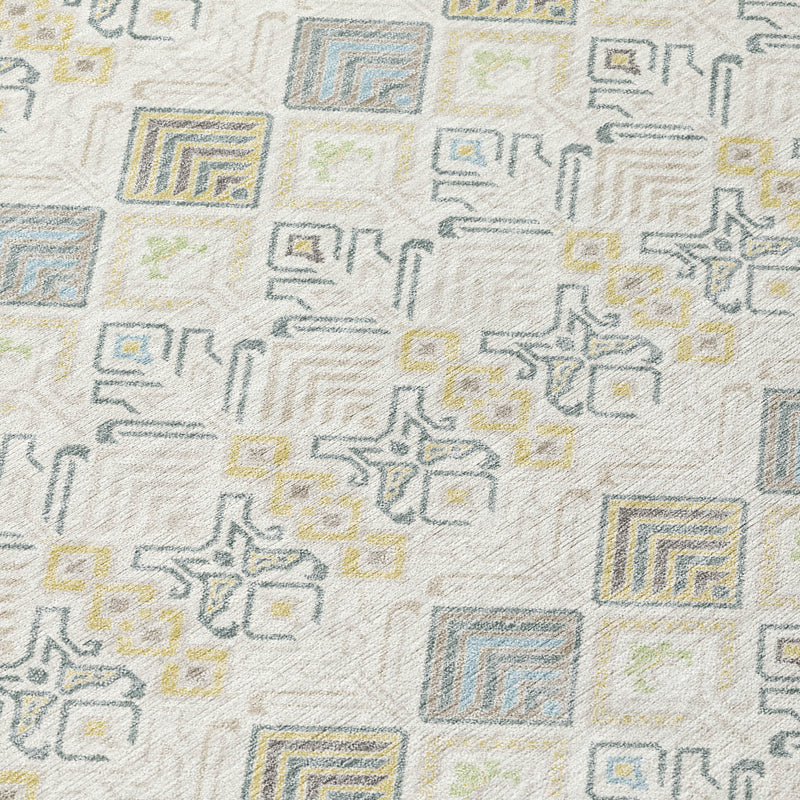 Close-up of geometric rug pattern with blue, wheat, and gray shapes on ivory