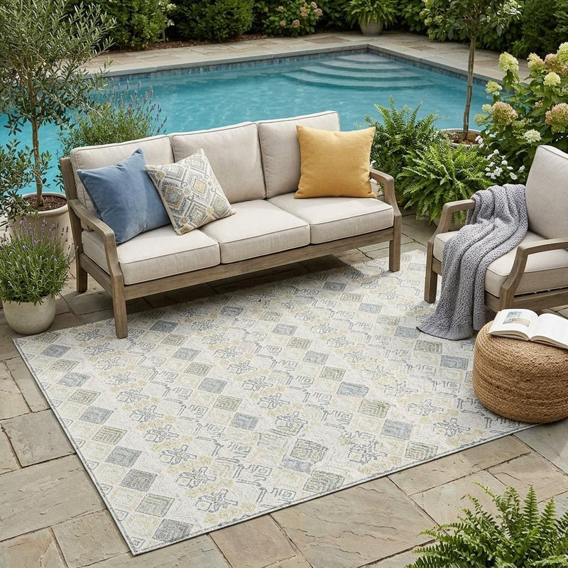 Outdoor patio area rug with geometric ivory, wheat, and blue pattern under seating