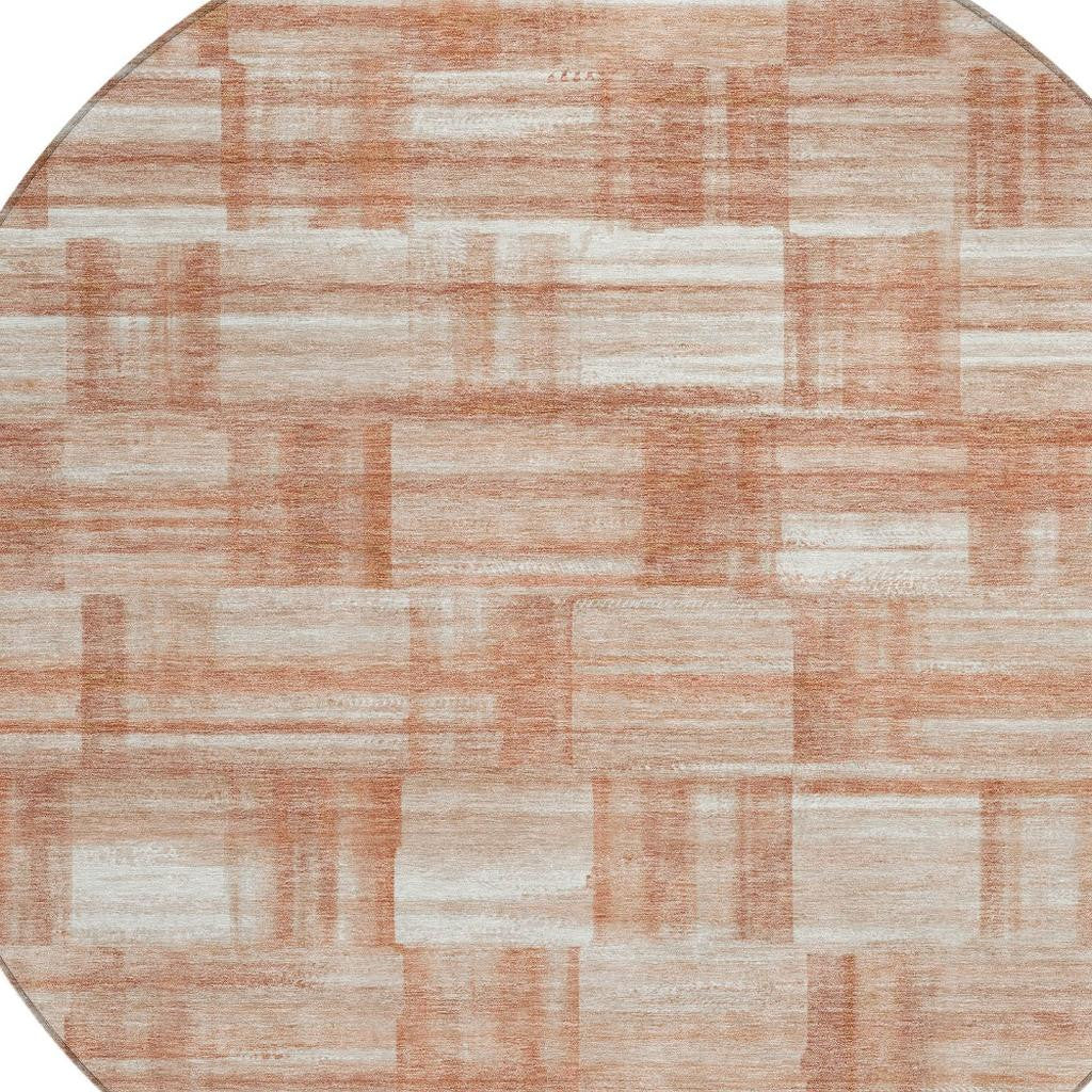 Round area rug with cream and salmon rectangular block pattern, copper-toned accents