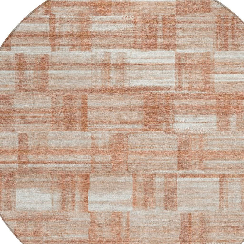 Round area rug with cream and salmon rectangular block pattern, copper-toned accents