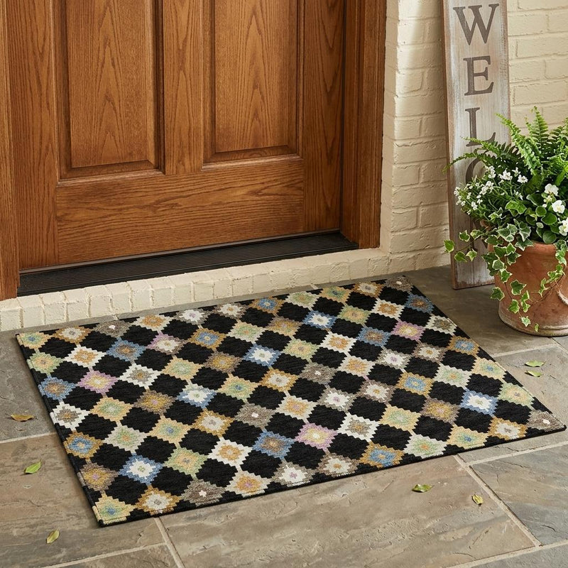 Black and multicolor geometric diamond area rug placed at entryway on tile floor
