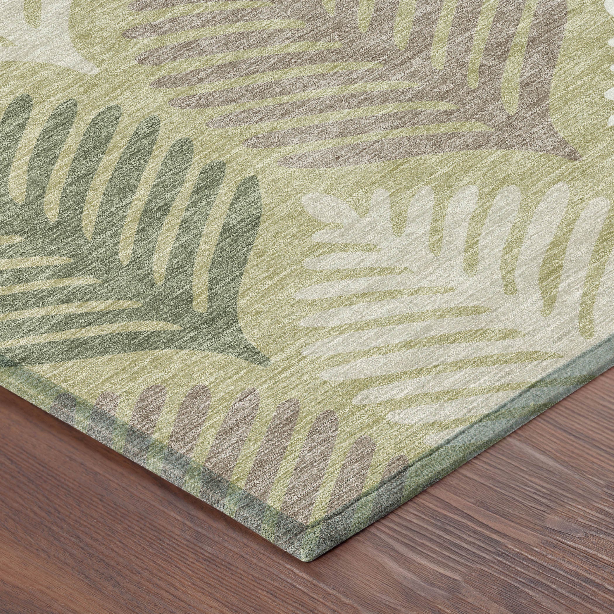 Corner view of area rug with muted green and ivory leaf pattern and bordered edge